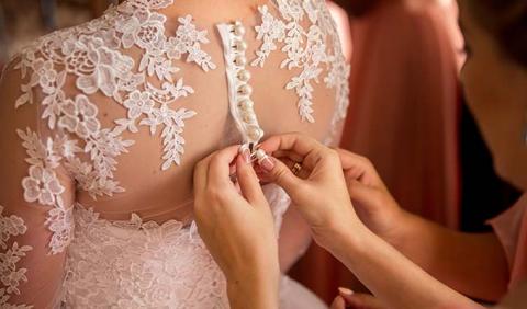 Mother helping button back of brides wedding dress